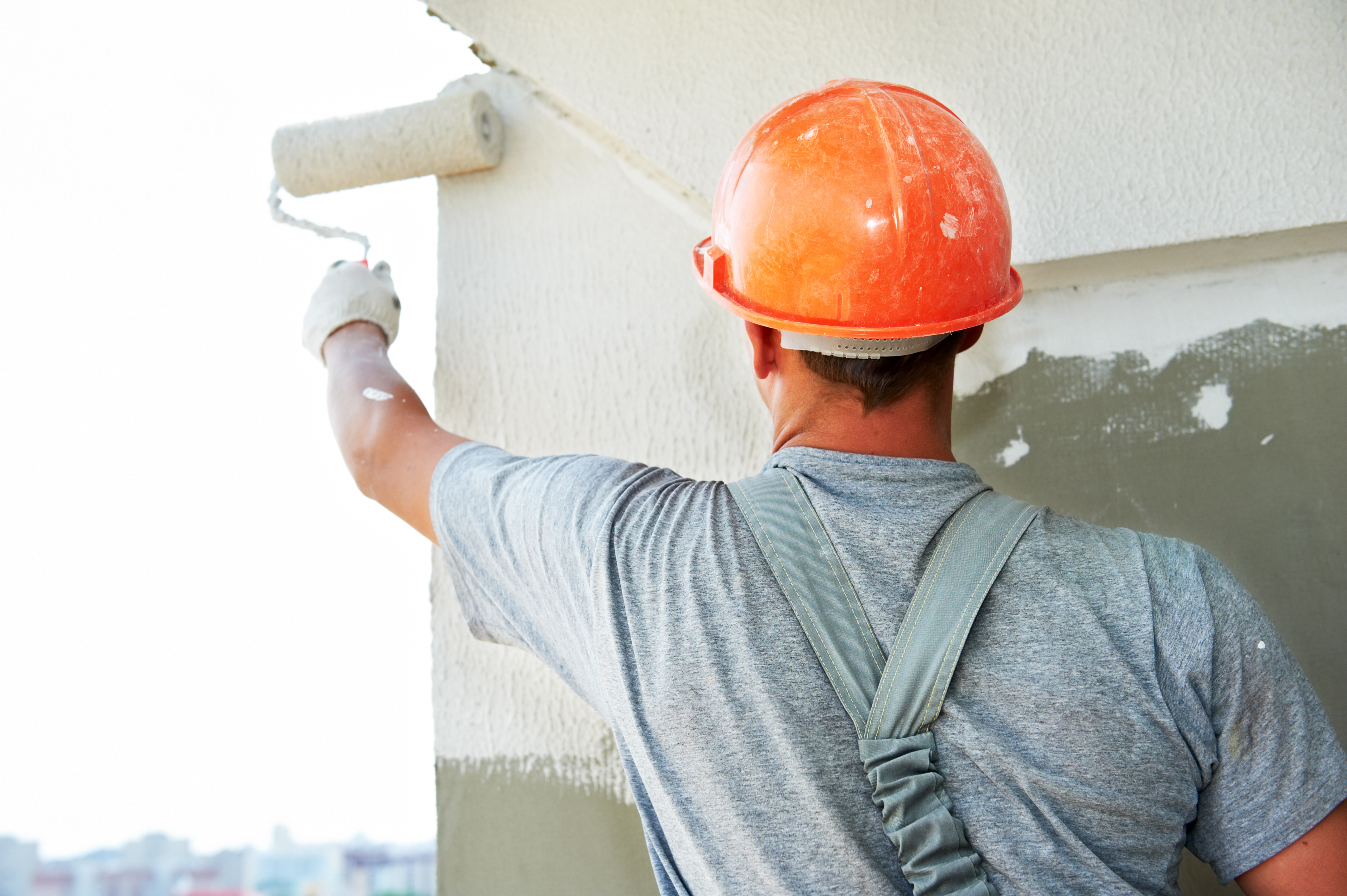 Painter applying a coating to an exterior wall with a roller